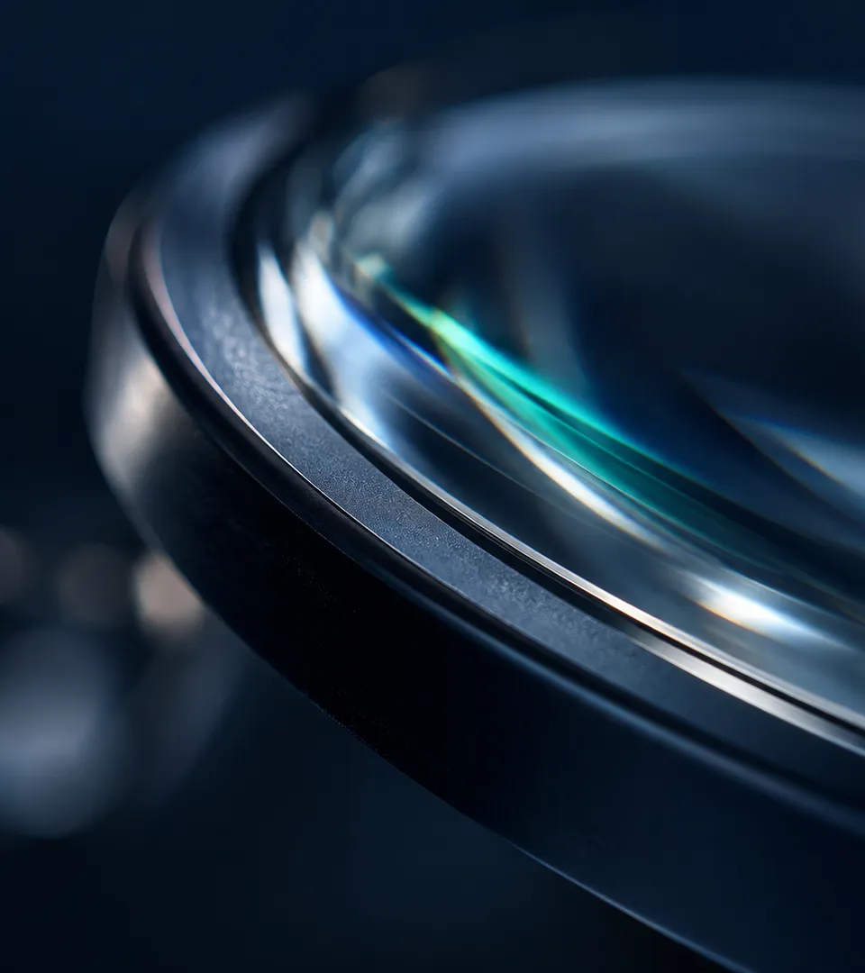 Gros plan sur la tranche courbe d’un verre optique cerclé de métal bleu nuit, avec un reflet turquoise et des halos de lumière.